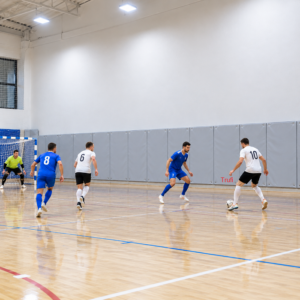 Panouri de protecție albastre montate pe peretele unei săli de sport, în spatele porții de futsal